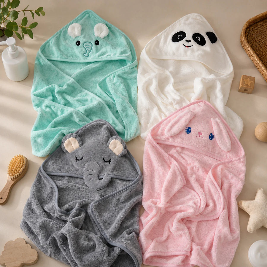 Four animal-themed hooded towels in green, white, gray, and pink on a beige surface.